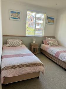 - une chambre avec 2 lits et une fenêtre dans l'établissement Coconuts - 2 balconies and stroll to choice of 2 beaches, à Nelson Bay