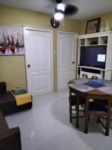 a living room with a table and a tv at City condo in Talisay