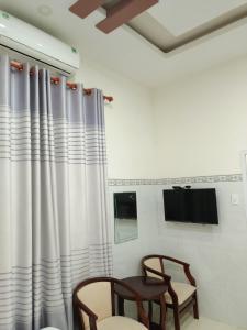 um quarto com duas cadeiras e uma janela com cortinas em Khách sạn Mộng An em Vinh Hy