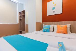 een slaapkamer met een bed met oranje en blauwe kussens bij Sans Hotel Rajawali Surabaya by RedDoorz in Krembangan