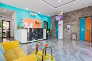 a lobby with a yellow couch and a tv at Sans Hotel Rajawali Surabaya by RedDoorz in Krembangan