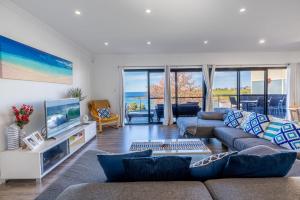 a living room with a couch and a tv at Sunrise on Easts 1 in Kiama