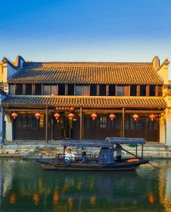 um barco na água em frente a um edifício em Tingjian Guli Private Bath Design Homestay - Nanxun Ancient Town Baijianlou Scenic Area em Huzhou
