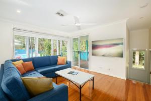 uma sala de estar com um sofá azul e uma mesa em Flynns on Surf Beach Villas em Port Macquarie