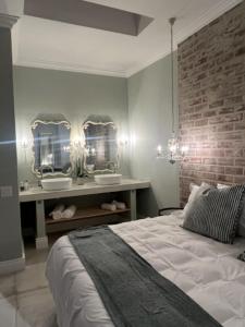 Two on Milner - OAK TREE COTTAGE - Stylish open-plan Guesthouse in Rondebosch في كيب تاون: غرفة نوم بسرير ومرآتين على الحائط