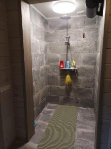 y baño con ducha y pared de piedra. en Pirts Jaunakmeni, en Priežmale