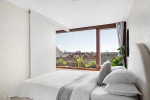 - une chambre avec un lit blanc et une grande fenêtre dans l'établissement Boutique Paddington Apartment with CBD Views, à Sydney
