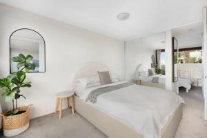 - une chambre blanche avec un grand lit et un miroir dans l'établissement Boutique Paddington Apartment with CBD Views, à Sydney
