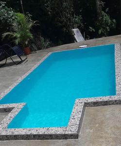 - une piscine bleue avec une chaise à côté dans l'établissement Casa Montaña & Spa Pital de San Carlos Costa Rica, à Pital