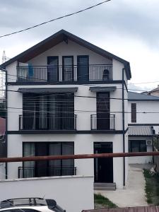 una casa blanca con balcones y un coche delante en Guesthouse Chrdili, en Tiflis