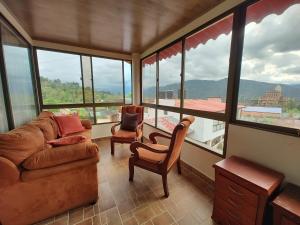 a living room with a couch and chairs and windows at Hospedaje Las Golondrinas in Tibirita