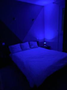 Habitación oscura con cama con iluminación azul en Champs Bernard, en Villefranche-de-Rouergue