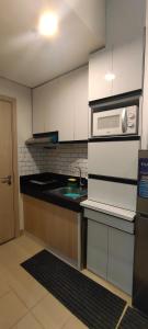 a kitchen with white cabinets and a sink and a microwave at Staycation by A&L in Marilao