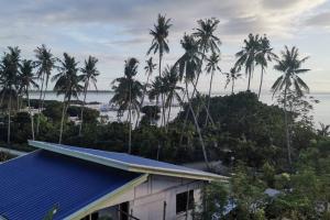ein Haus mit einem blauen Dach und Palmen in der Unterkunft Sunset Ocean View @ Breeze Life. in Panglao