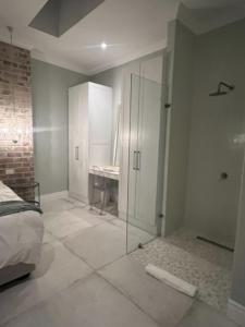 1 dormitorio con ducha de cristal y 1 cama en Two on Milner - ARUM COTTAGE - Stylish open-plan Guesthouse in Rondebosch en Ciudad del Cabo