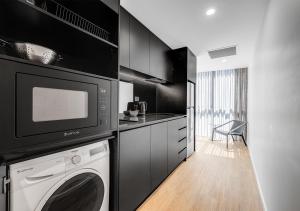 a kitchen with a washing machine and a microwave at Rambla at South City SQ in Brisbane