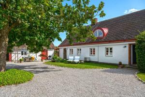 une maison blanche avec un arbre et une allée en gravier dans l'établissement Farmhouse in Sweden 15 minutes from Malmö, à Trelleborg