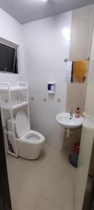 uma casa de banho branca com um WC e um lavatório em lumut manjung homestay john faten em Lumut