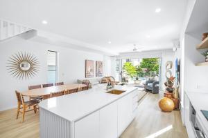 棕榈湾The Santana Collection TWO - Luxury Accomodation in the heart of Palm Cove的厨房以及带白色橱柜和桌子的用餐室。