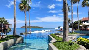 una piscina con palme e l'oceano di Nora Buri Resort & Spa - SHA Extra Plus a Chaweng Beach