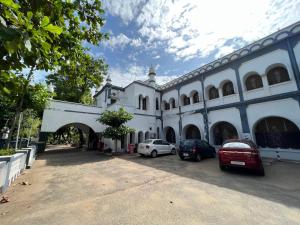 Hotel TamilNadu - Thanjavur في ثانجافور: مبنى أبيض فيه سيارات تقف في موقف للسيارات