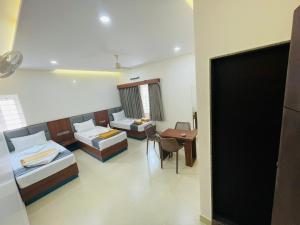 Habitación con 2 camas, mesa y sillas en Hotel Royal Inn Lodge Dharwad, en Dharwad