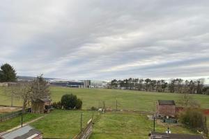een groot groen veld met een gebouw op de achtergrond bij 2 Bed Apt - P&J Live, AWPR, Airport in Aberdeen