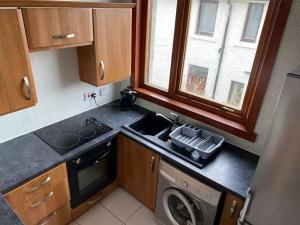 a small kitchen with a sink and a dishwasher at 2 Bed Apt - P&J Live, AWPR, Airport in Aberdeen