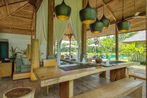 een woonkamer met een houten tafel en stoelen bij Villa Lumia Bali in Ubud