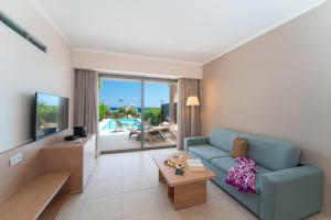 KRESTEN ROYAL Euphoria Resort في كاليثيا رودس: غرفة معيشة مع أريكة زرقاء وتلفزيون