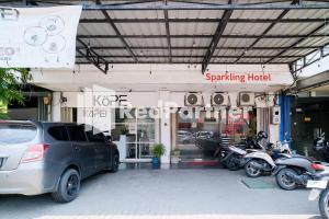 un aparcamiento con coches y motocicletas estacionados frente a un edificio en RedDoorz at Sparkling Hotel Surabaya, en Surabaya