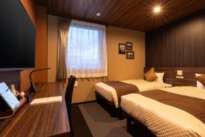 a hotel room with two beds and a desk and a television at The Celecton Gotemba Interchange in Gotemba
