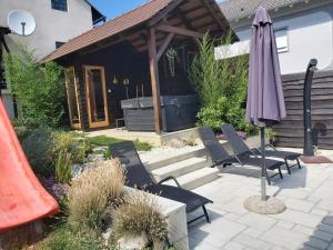 eine Terrasse mit Stühlen und einem Sonnenschirm vor einem Haus in der Unterkunft Holiday Home Kalnik in Kalnik