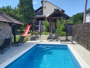 a pool with chairs and a slide in a backyard at Holiday Home Kalnik in Kalnik