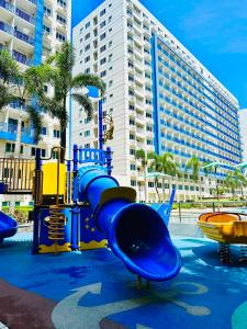un parque infantil con un tobogán frente a un edificio en Sea Residences Apartment by Kevin Alano, en Manila