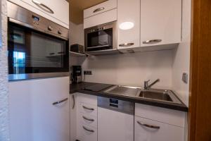 a kitchen with white cabinets and a sink and a microwave at Ferienwohnungen Dormann 