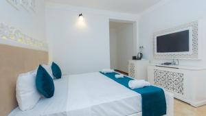 a white bedroom with a bed and a tv at Lillywoods NV Beach Resort in Calangute