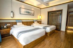 two beds in a room with wooden floors at 张家界惹莲心栖墅·精品民宿 in Zhangjiajie