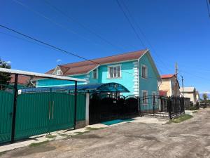 a blue and green house with a green fence at Guesthouse Alakol in Karakol