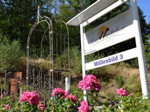 Hotel Wanderlust B&B في غرنباخ: علامة أمام حديقة بها زهور