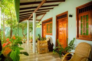 een veranda van een huis met planten en een houten deur bij Nehansa Resort and safari in Tissamaharama
