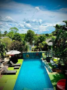 a large swimming pool with chairs and an umbrella at Na Na Doo Homestay in Chiang Rai