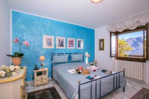 1 dormitorio con cama y pared azul en Veranda di Menaggio, en Menaggio