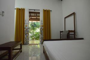 a bedroom with a bed and a mirror and yellow curtains at Binara Home Stay in Polonnaruwa
