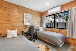 Habitación con 2 camas, escritorio y ventana. en Sunset Cottage - Waikanae Beach Holiday Home, en Waikanae