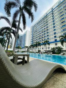 una silla y una mesa junto a la piscina en Sea Residences Apartment by Kevin Alano, en Manila