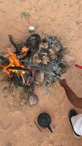 una parrilla con algo de comida en la tierra en Enad desert camp en Wadi Rum