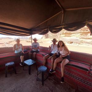 un grupo de personas sentadas en un autobús en el desierto en Enad desert camp en Wadi Rum