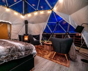 - une chambre dans une tente en forme de dôme avec un lit et des chaises dans l'établissement Arctic Dome Gudbrandsdalen, à Sør-Fron