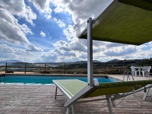 聖塞韋里諾馬爾凱的住宿－Agriturismo Collamato，游泳池旁甲板上的椅子